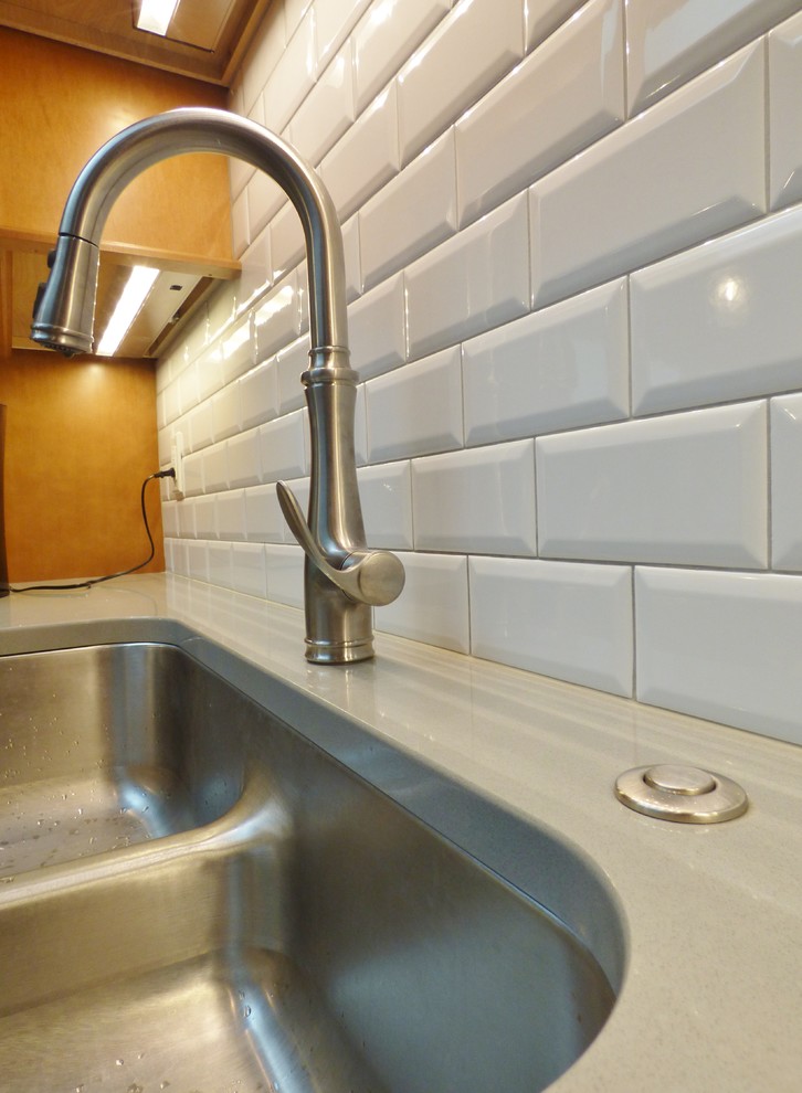 Example of a transitional l-shaped porcelain tile eat-in kitchen design with an undermount sink, recessed-panel cabinets, medium tone wood cabinets, quartz countertops, white backsplash, subway tile backsplash, stainless steel appliances and an island