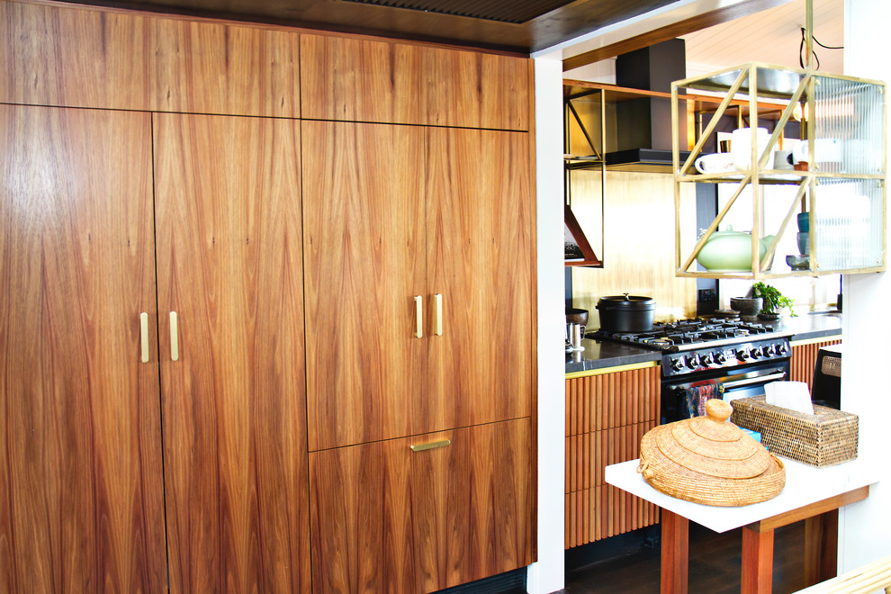 Photo of an industrial galley eat-in kitchen in Brisbane with an undermount sink, louvered cabinets, medium wood cabinets, granite benchtops, black appliances, dark hardwood floors, with island and black floor.