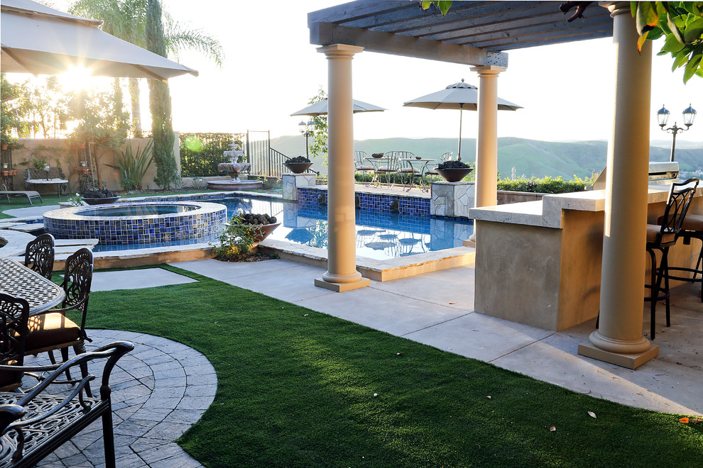 Photo of a mid-sized transitional backyard custom-shaped natural pool in Orange County with a hot tub and natural stone pavers.