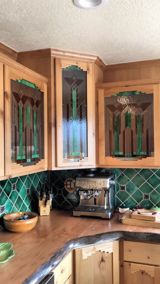 Example of a mid-sized mountain style u-shaped porcelain tile enclosed kitchen design in Phoenix with an undermount sink, shaker cabinets, light wood cabinets, wood countertops, green backsplash, stainless steel appliances and an island