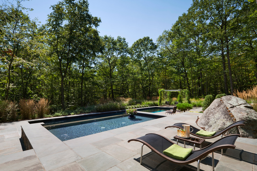 Inspiration for a modern backyard rectangular lap pool in New York with a hot tub and natural stone pavers.