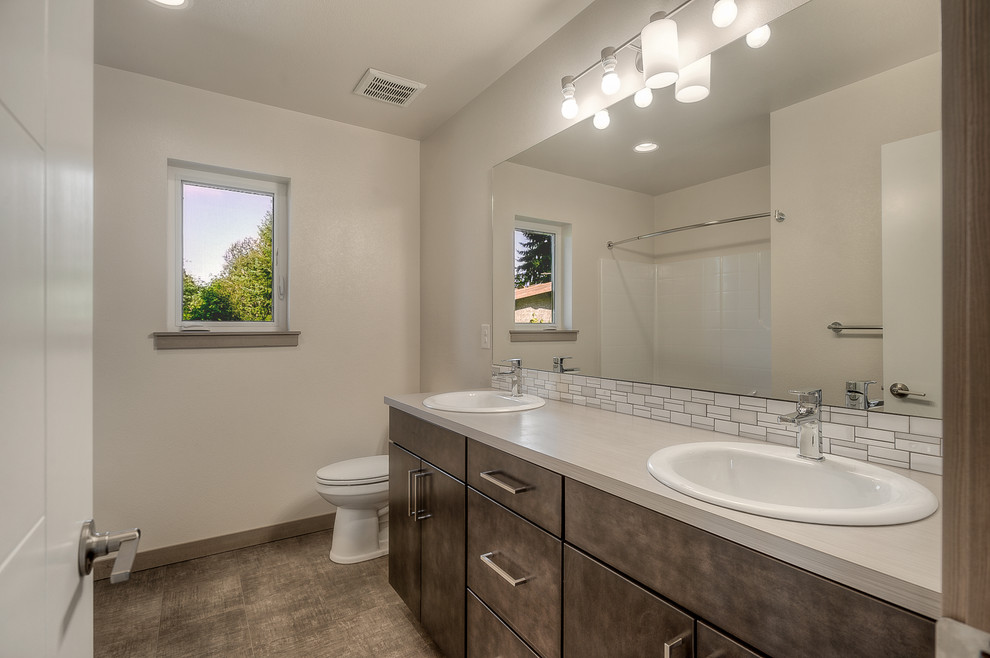 Inspiration for a mid-sized contemporary bathroom in Seattle with flat-panel cabinets, brown cabinets, an alcove tub, an alcove shower, a one-piece toilet, white tile, mosaic tile, beige walls, linoleum floors, a drop-in sink, laminate benchtops, brown floor and a shower curtain.