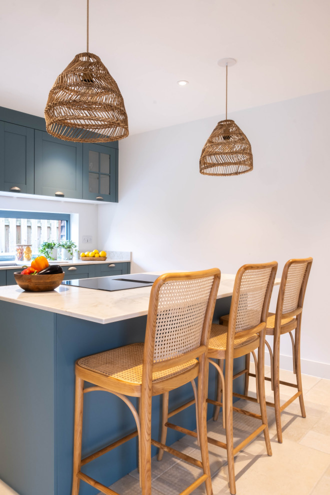 Example of a mid-sized trendy porcelain tile and beige floor eat-in kitchen design in Gloucestershire with an integrated sink, shaker cabinets, blue cabinets, quartz countertops, white countertops, paneled appliances and an island