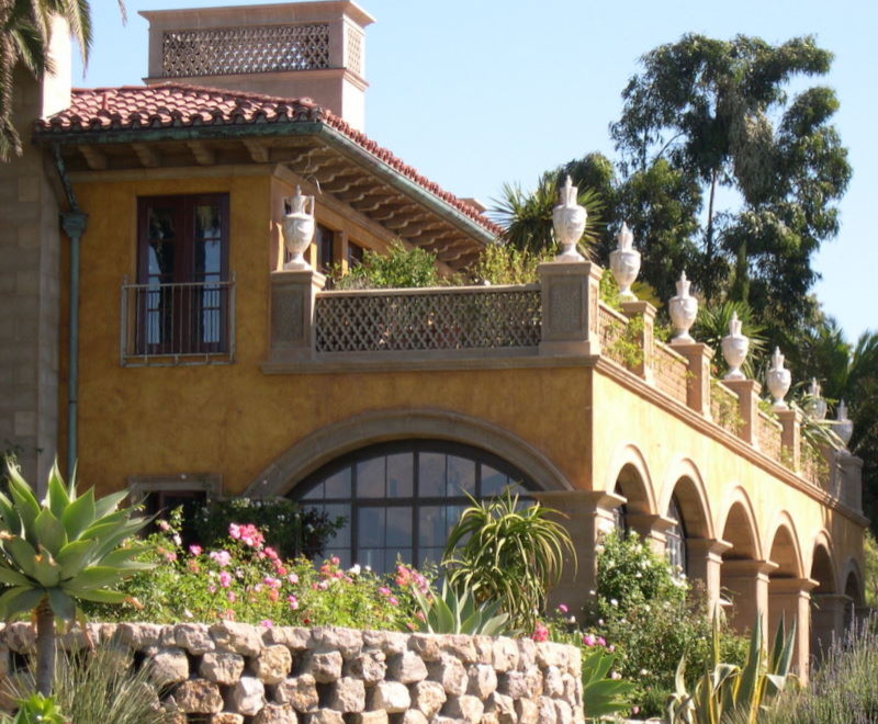 This is an example of a large mediterranean two-storey stucco beige house exterior in Santa Barbara with a hip roof and a tile roof.