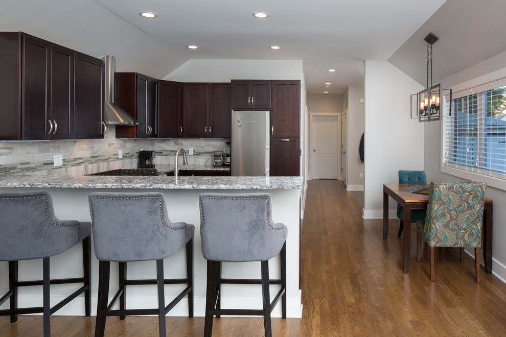 Inspiration for a small transitional u-shaped medium tone wood floor open concept kitchen remodel in Milwaukee with an undermount sink, shaker cabinets, dark wood cabinets, granite countertops, gray backsplash, ceramic backsplash, stainless steel appliances and no island