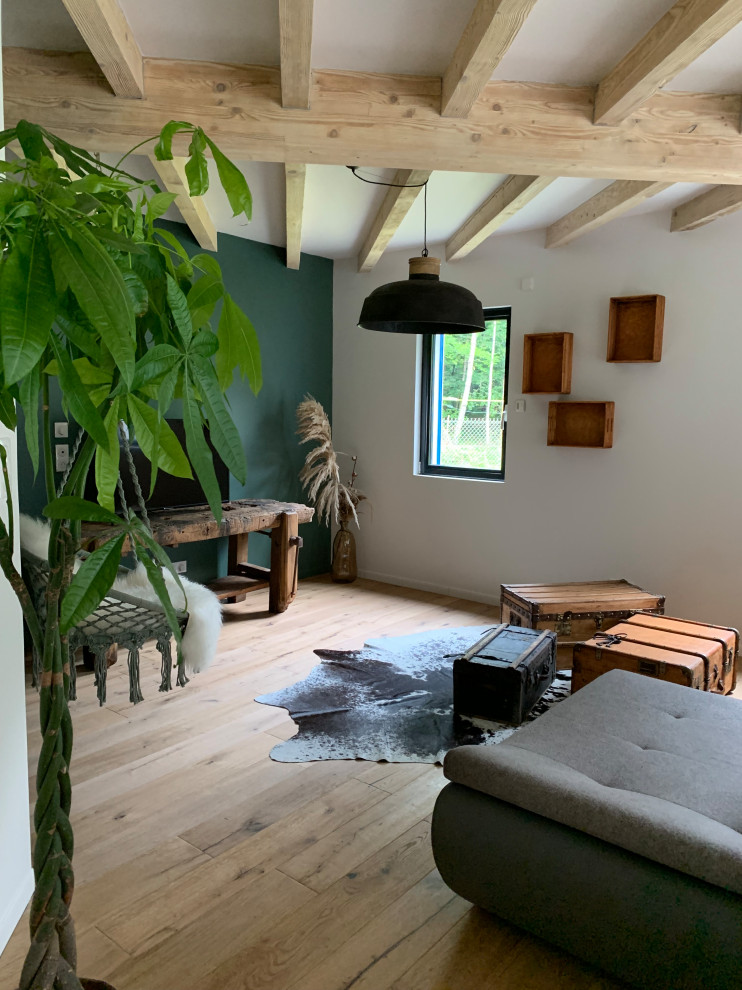 Réalisation d'un grand salon champêtre ouvert avec un mur vert, parquet clair, un poêle à bois, un manteau de cheminée en carrelage, un sol marron et un plafond en bois.
