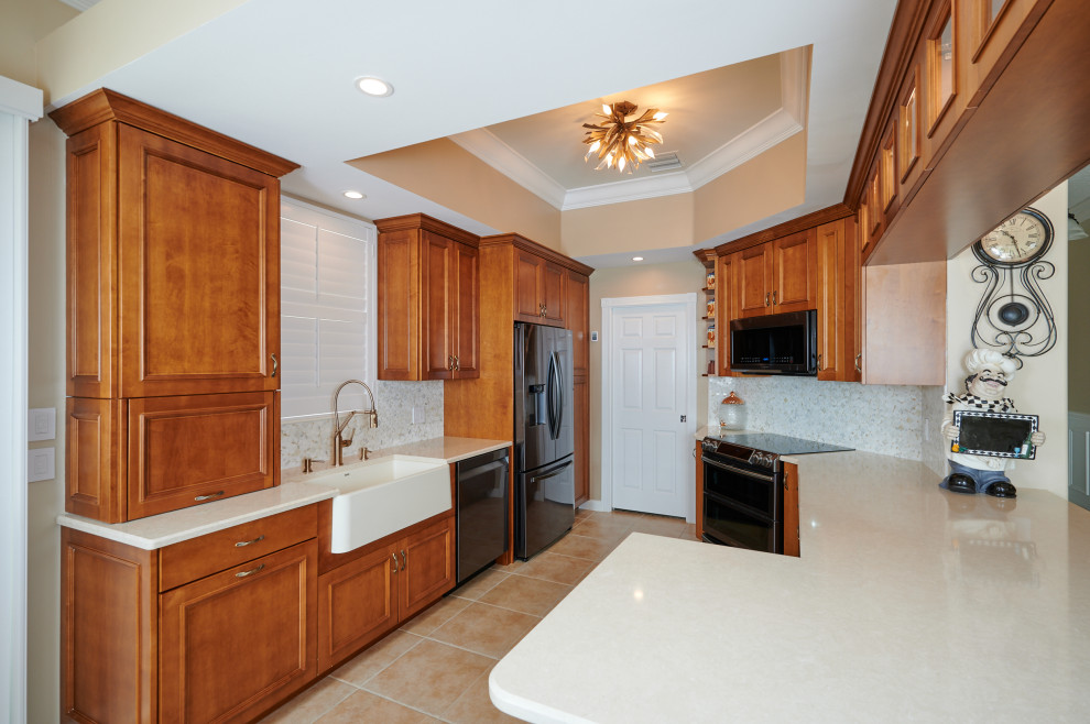 Mid-sized transitional galley porcelain tile, beige floor and tray ceiling kitchen photo with a farmhouse sink, recessed-panel cabinets, medium tone wood cabinets, quartz countertops, multicolored backsplash, marble backsplash, stainless steel appliances, a peninsula and beige countertops