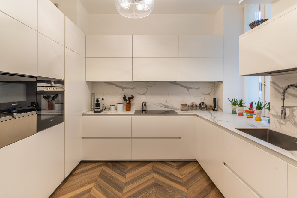 Foto de cocinas en U contemporáneo grande sin isla con suelo de madera clara, puertas de armario blancas y electrodomésticos de acero inoxidable