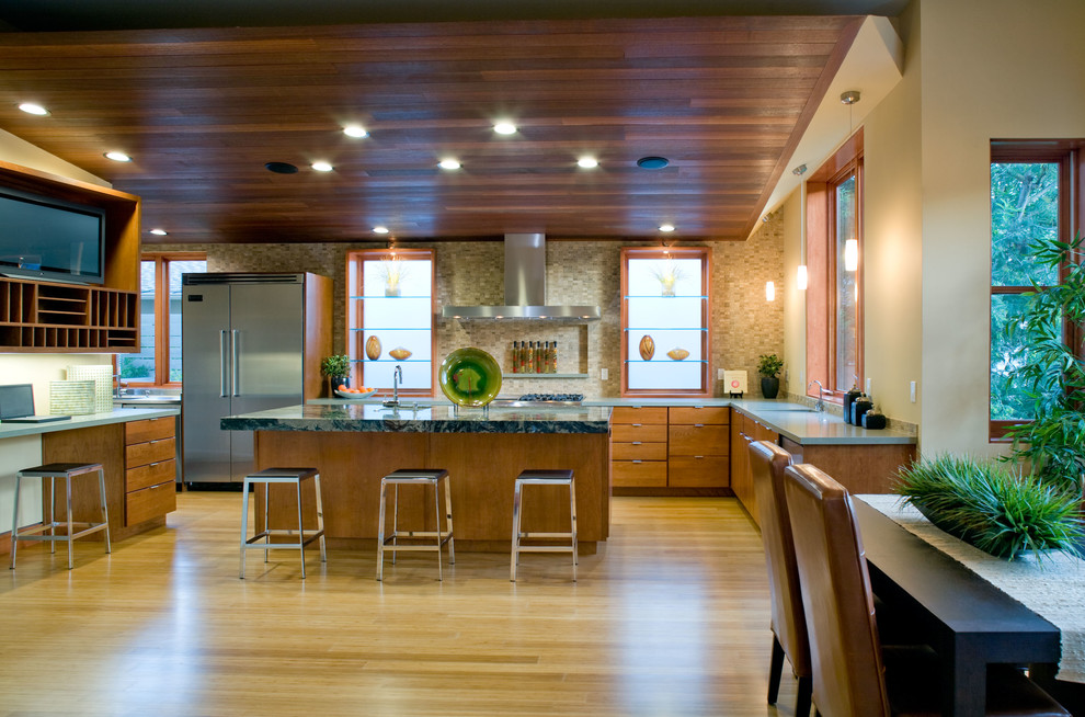 Large contemporary l-shaped eat-in kitchen in Los Angeles with an undermount sink, flat-panel cabinets, medium wood cabinets, quartz benchtops, brown splashback, stone tile splashback, stainless steel appliances, bamboo floors and with island.