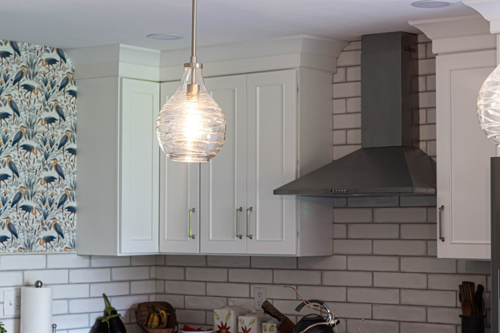 Inspiration for a mid-sized transitional l-shaped porcelain tile and gray floor eat-in kitchen remodel with an undermount sink, flat-panel cabinets, white cabinets, quartz countertops, white backsplash, subway tile backsplash, stainless steel appliances, an island and white countertops
