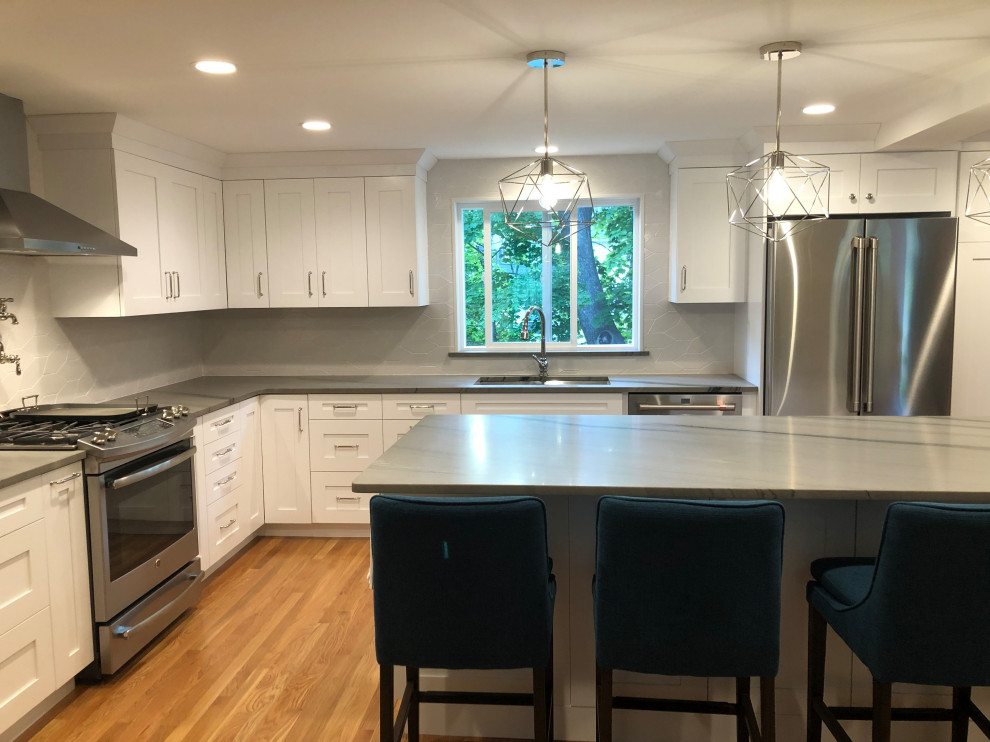 Large transitional l-shaped open plan kitchen in Boston with shaker cabinets, white cabinets, quartzite benchtops, grey splashback, with island and grey benchtop.