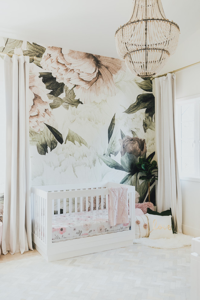 Small transitional nursery in Los Angeles with light hardwood floors and multi-coloured walls for girls.