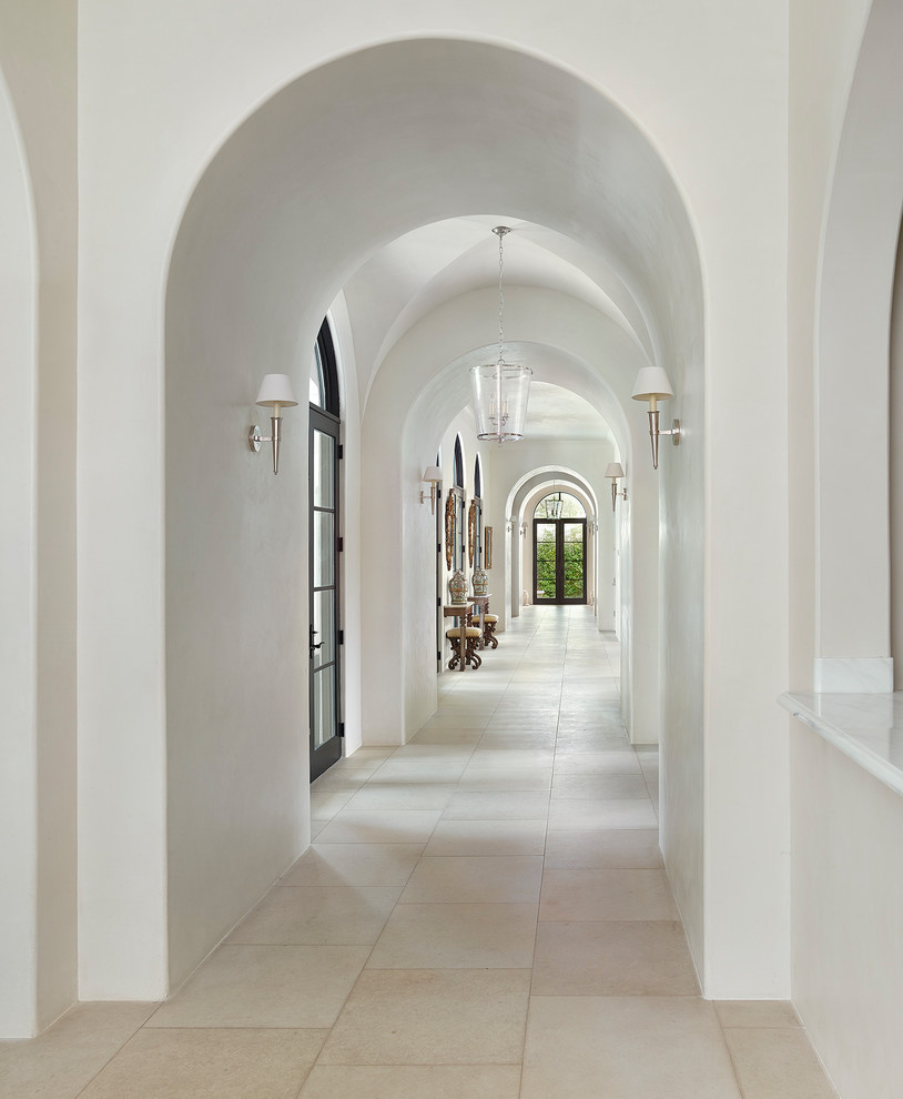 This is an example of a mediterranean hallway in Dallas with white walls and beige floor.