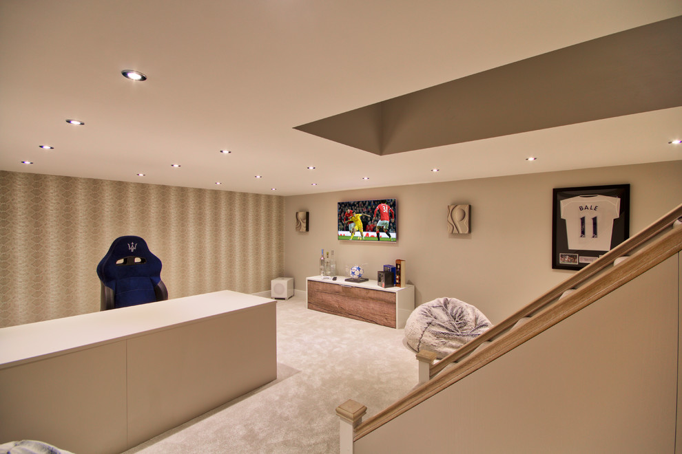 This is an example of a mid-sized contemporary fully buried basement in Essex with beige walls and carpet.