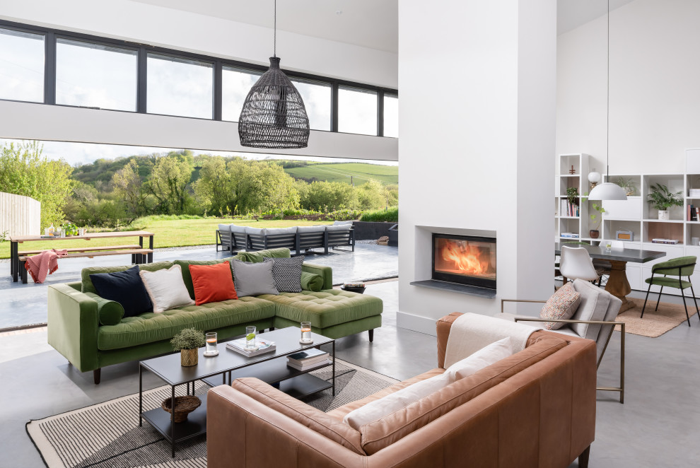 Example of a large trendy open concept gray floor living room design in Devon with white walls and a two-sided fireplace