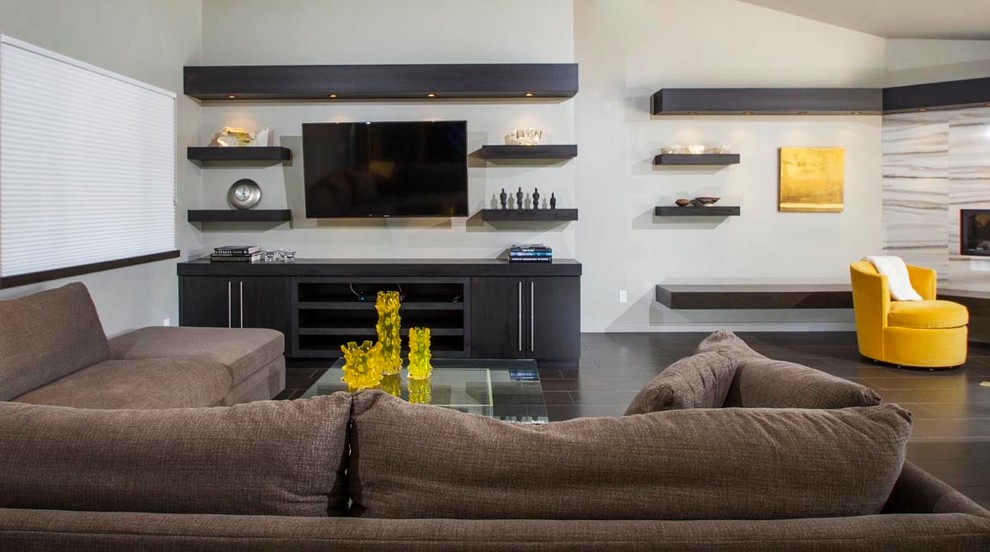 This is an example of a mid-sized contemporary open concept living room in San Diego with grey walls, porcelain floors, a corner fireplace, a stone fireplace surround, a wall-mounted tv and brown floor.