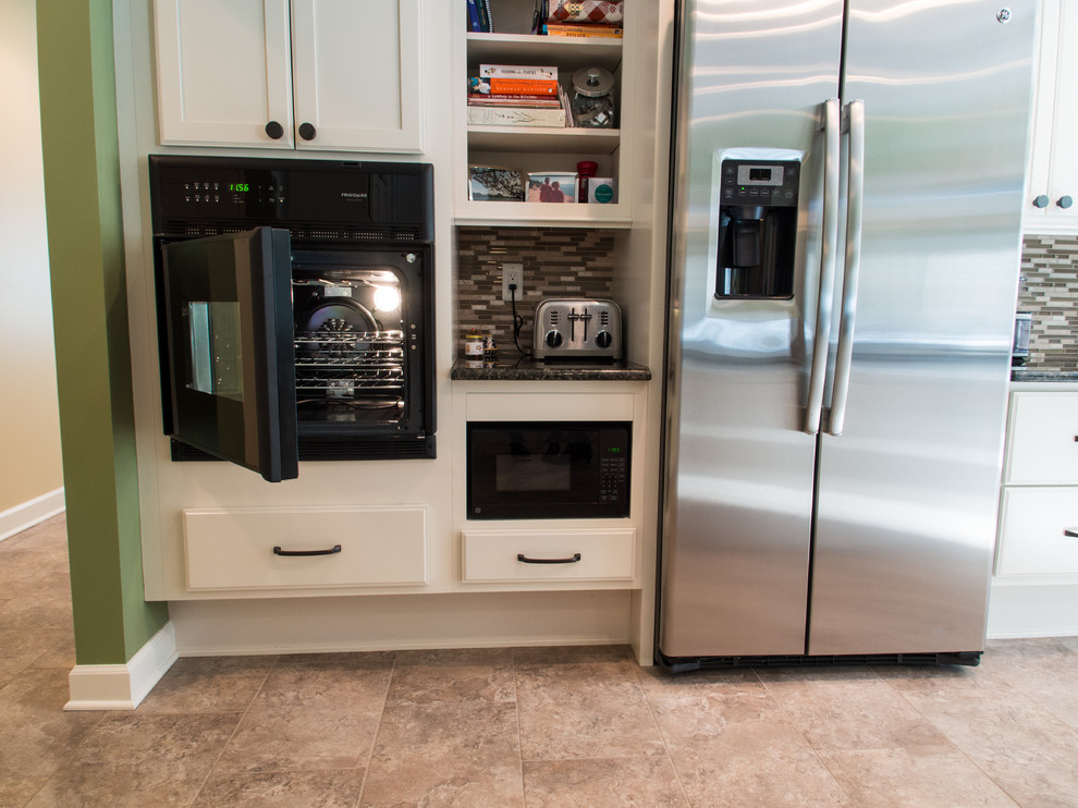 Example of a large transitional u-shaped porcelain tile eat-in kitchen design with an undermount sink, recessed-panel cabinets, white cabinets, granite countertops, multicolored backsplash, glass tile backsplash, stainless steel appliances and an island
