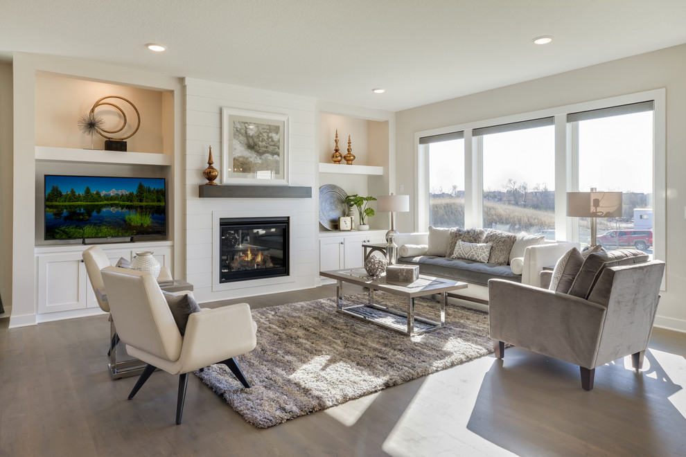 Inspiration for a transitional open concept living room in Minneapolis with beige walls, dark hardwood floors, a standard fireplace, a freestanding tv, brown floor and a wood fireplace surround.