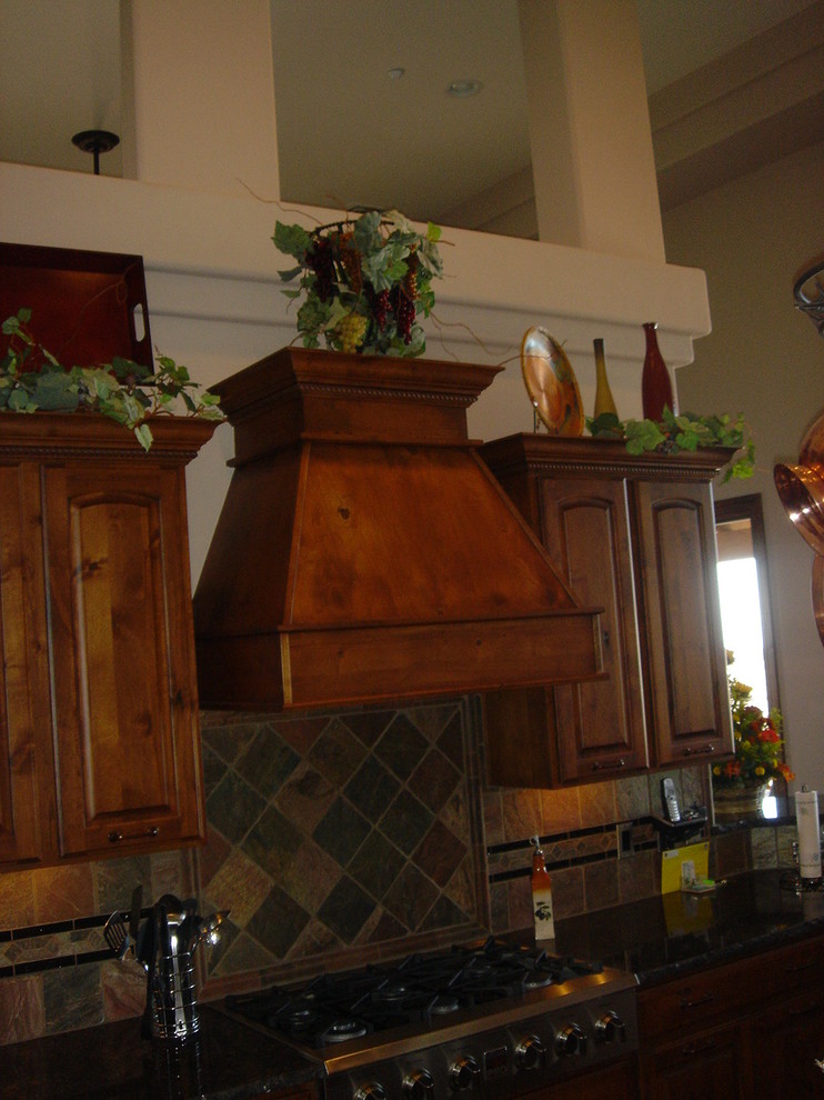 Example of a large transitional u-shaped eat-in kitchen design with raised-panel cabinets, dark wood cabinets, granite countertops, beige backsplash, stone tile backsplash, stainless steel appliances and an island