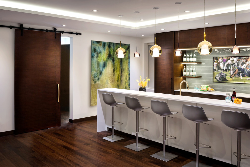 Inspiration for a contemporary galley seated home bar in Vancouver with flat-panel cabinets, dark wood cabinets, quartz benchtops, dark hardwood floors, grey splashback, glass tile splashback and brown floor.
