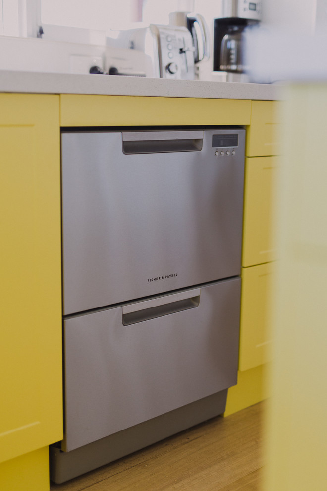 Photo of a tropical kitchen in Hobart with yellow cabinets and with island.