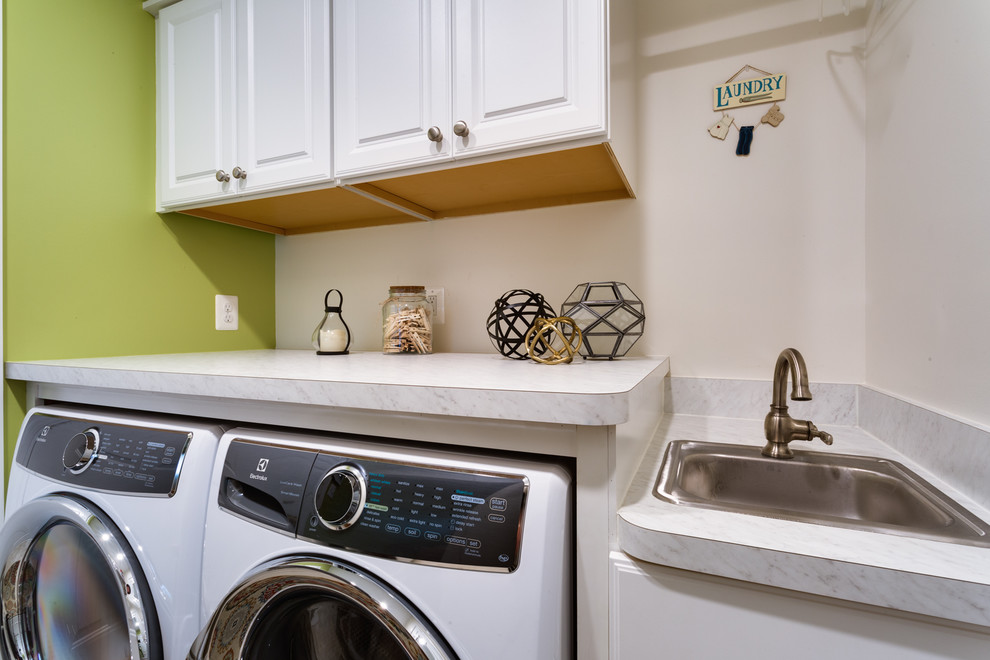 Photo of a small traditional galley dedicated laundry room in DC Metro with a drop-in sink, raised-panel cabinets, white cabinets, quartz benchtops, beige walls, ceramic floors, a side-by-side washer and dryer, grey floor and white benchtop.