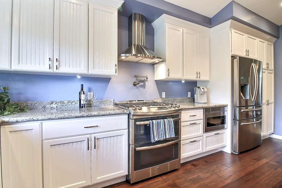Immagine di una grande cucina contemporanea con lavello sottopiano, ante bianche, paraspruzzi blu, elettrodomestici in acciaio inossidabile, parquet scuro, pavimento marrone e top grigio