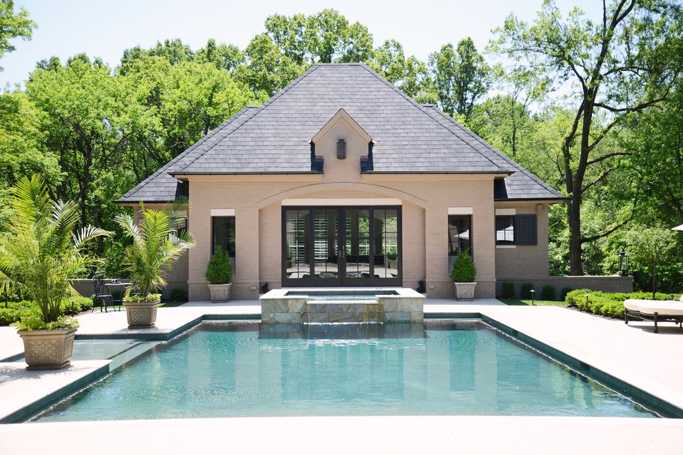 This is an example of a transitional backyard rectangular infinity pool in St Louis with a pool house.