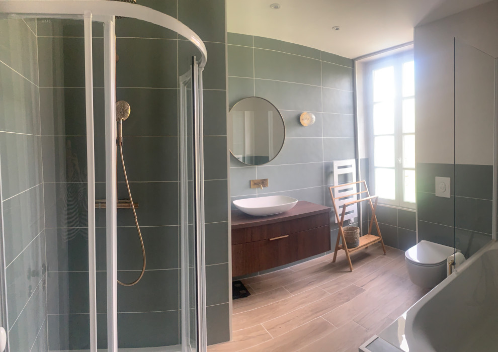 Пример оригинального дизайна: ванная комната среднего размера в современном стиле с плоскими фасадами, темными деревянными фасадами, полновстраиваемой ванной, угловым душем, инсталляцией, зеленой плиткой, керамической плиткой, зелеными стенами, полом из плитки под дерево, настольной раковиной, столешницей из ламината, коричневым полом, душем с раздвижными дверями, разноцветной столешницей и тумбой под одну раковину