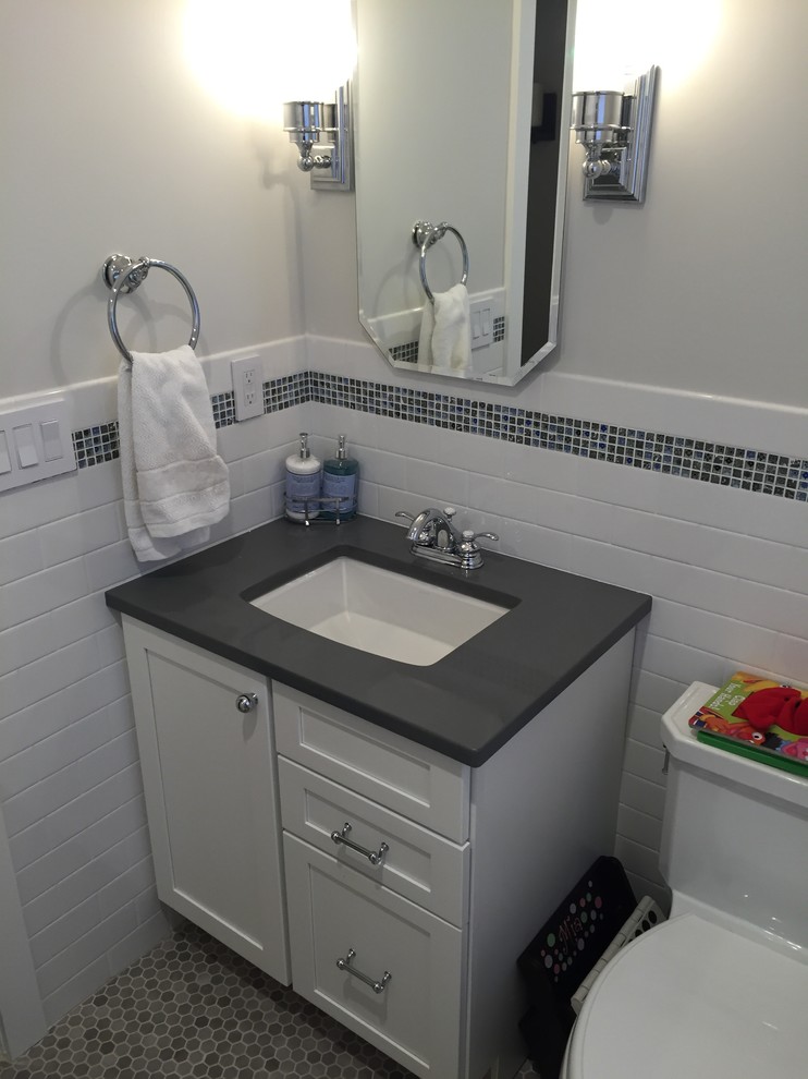 Traditional bathroom in New York with white cabinets, a shower/bathtub combo, white tile, subway tile, grey walls, an undermount sink, grey floor and a shower curtain.