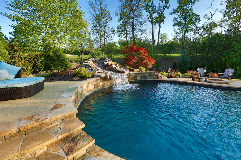Large traditional backyard custom-shaped natural pool in Atlanta with a water feature and stamped concrete.