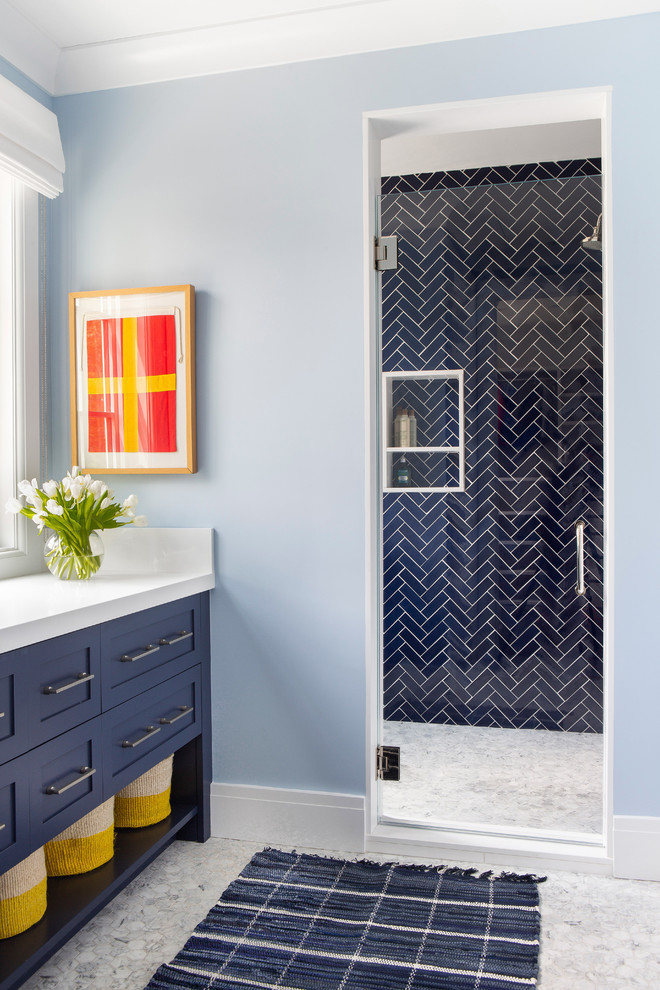 This is an example of a mid-sized country 3/4 bathroom in New York with shaker cabinets, blue cabinets, an alcove shower, blue tile, blue walls, a hinged shower door and white benchtops.