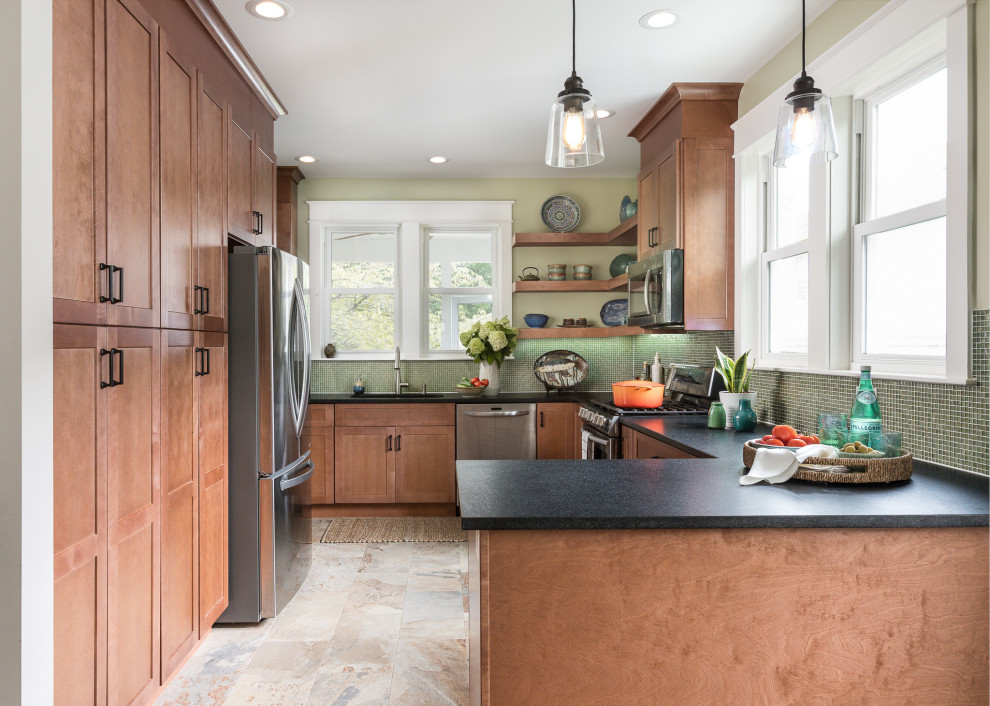 Design ideas for a mid-sized transitional l-shaped eat-in kitchen in DC Metro with an undermount sink, shaker cabinets, granite benchtops, green splashback, glass tile splashback, stainless steel appliances, porcelain floors, no island, multi-coloured floor, black benchtop and medium wood cabinets.