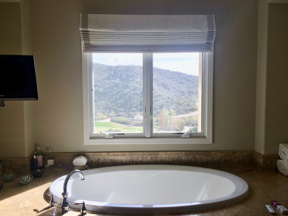 Example of a mid-sized transitional drop-in bathtub design in Orange County with beige walls