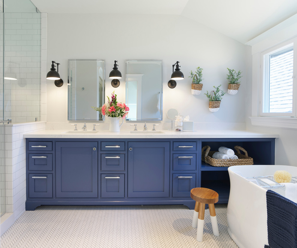 Photo of a mid-sized transitional master bathroom in San Francisco with shaker cabinets, blue cabinets, a freestanding tub, an alcove shower, a one-piece toilet, white tile, ceramic tile, white walls, mosaic tile floors, an undermount sink, engineered quartz benchtops, white floor, a hinged shower door, white benchtops, a niche, a double vanity and a built-in vanity.