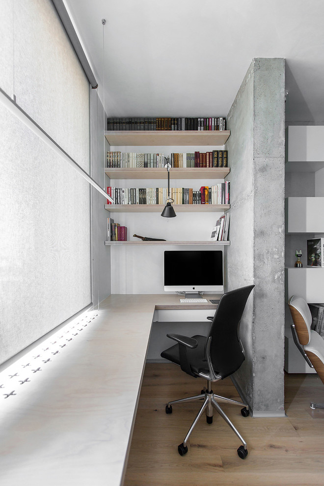На фото: рабочее место с серыми стенами, светлым паркетным полом и встроенным рабочим столом с