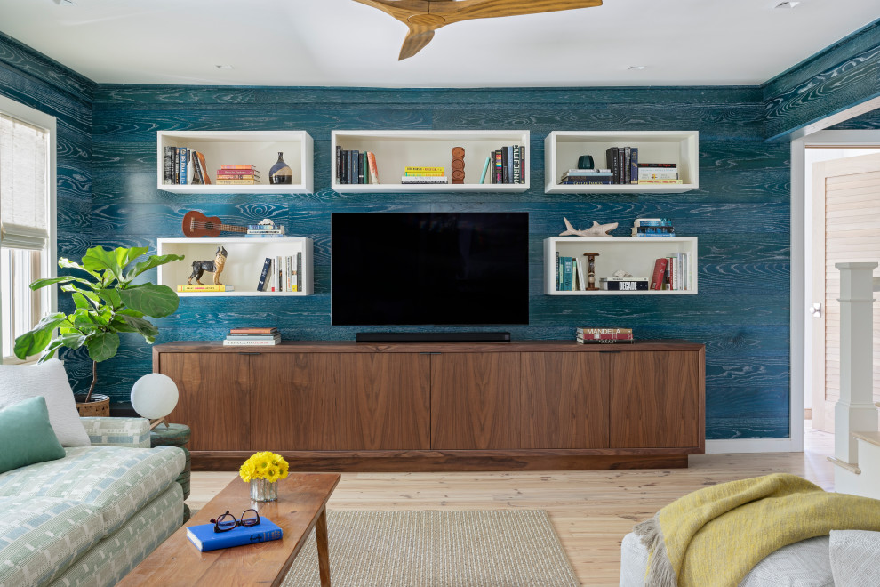 Imagen de sala de estar cerrada marinera pequeña con paredes azules, suelo de madera clara, televisor colgado en la pared y madera