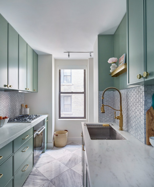 Elegant sage green galley kitchen cabinets with brass hardware, marble countertops, hexagon tile backsplash, and a narrow corridor layout with natural light