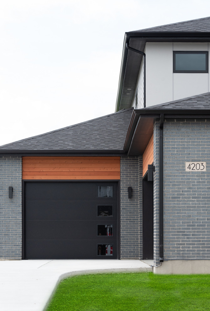 This is an example of a large modern two-storey brick grey house exterior in Chicago with a butterfly roof and a shingle roof.