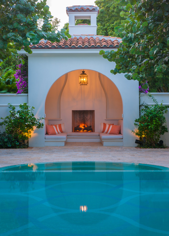 Inspiration for an expansive mediterranean round pool in Miami with a pool house and natural stone pavers.