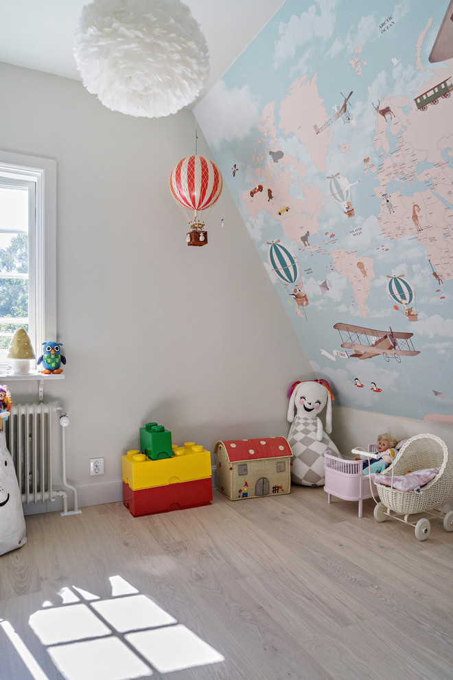 Photo of a scandinavian toddler room for girls in Stockholm with multi-coloured walls and light hardwood floors.