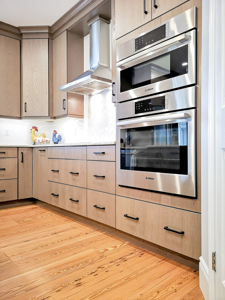 Example of a large transitional u-shaped light wood floor and brown floor eat-in kitchen design with an undermount sink, flat-panel cabinets, beige cabinets, quartz countertops, subway tile backsplash, stainless steel appliances, an island and white countertops