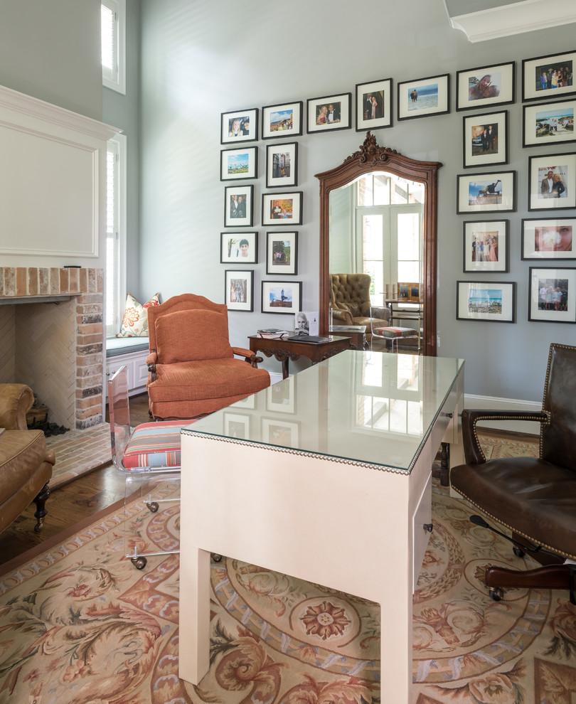 This is an example of a mid-sized contemporary study room in Houston with grey walls, medium hardwood floors, no fireplace, a brick fireplace surround and a freestanding desk.