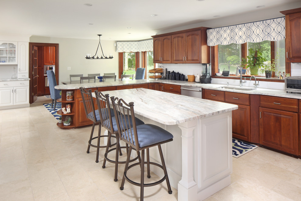 Design ideas for a large transitional u-shaped eat-in kitchen in Boston with an undermount sink, raised-panel cabinets, medium wood cabinets, granite benchtops, white splashback, subway tile splashback, stainless steel appliances, porcelain floors, with island, beige floor and white benchtop.