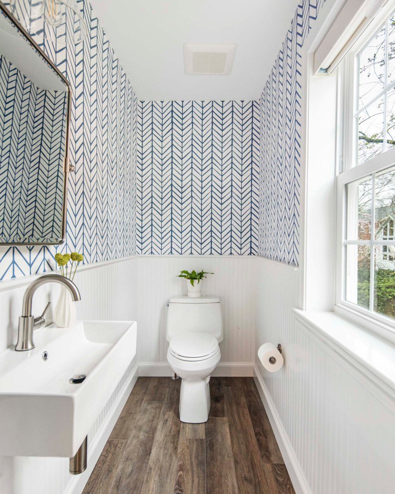 Cette image montre un WC et toilettes design avec des portes de placard blanches, WC à poser, un mur blanc, parquet foncé, un sol marron, un plan de toilette blanc et meuble-lavabo suspendu.