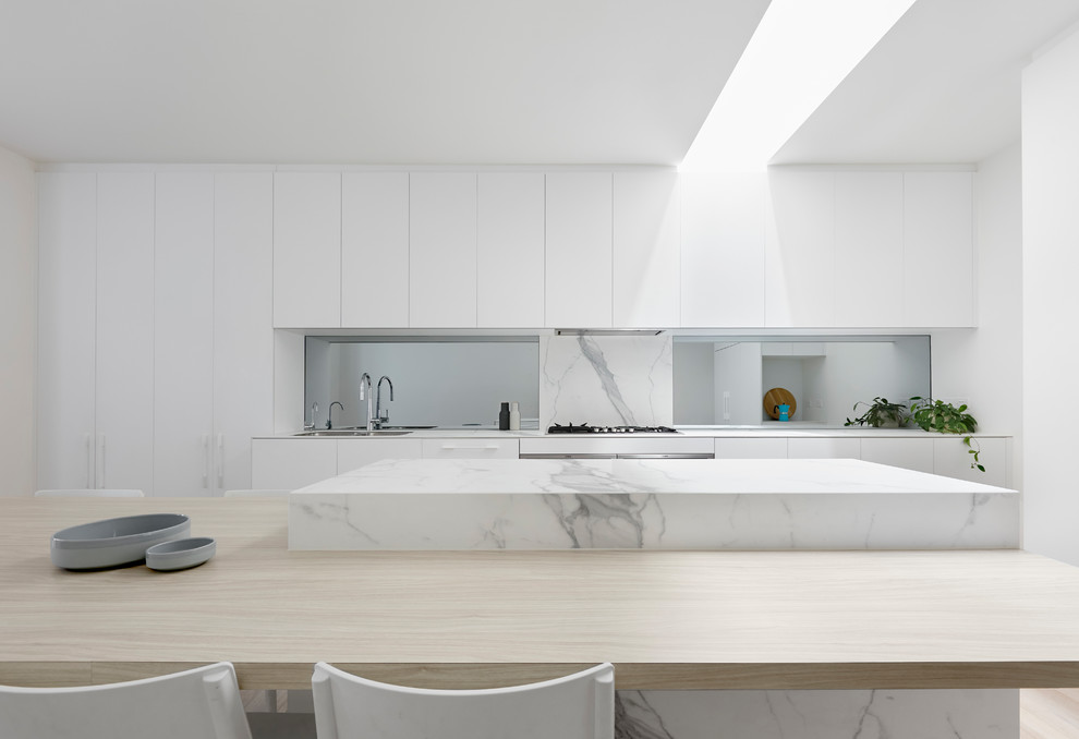 This is an example of a large modern single-wall kitchen pantry in Melbourne with beaded inset cabinets, white cabinets, marble benchtops, white splashback, marble splashback, stainless steel appliances, slate floors, with island, white floor and white benchtop.