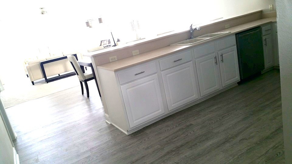 Example of a mid-sized transitional u-shaped medium tone wood floor eat-in kitchen design with a drop-in sink, raised-panel cabinets, white cabinets, laminate countertops, stainless steel appliances and no island
