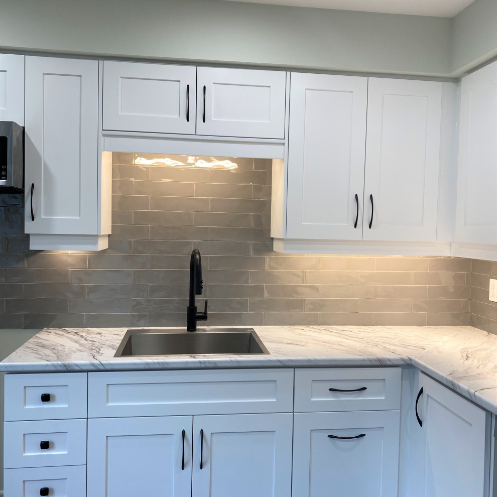 Inspiration for a mid-sized transitional galley vinyl floor eat-in kitchen remodel in Toronto with a drop-in sink, shaker cabinets, white cabinets, laminate countertops, gray backsplash and stainless steel appliances