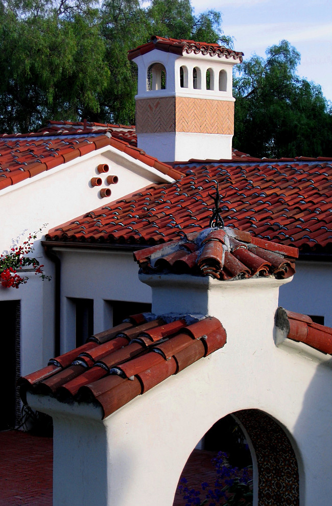 This is an example of a mid-sized mediterranean one-storey stucco white house exterior in Santa Barbara with a clipped gable roof and a tile roof.