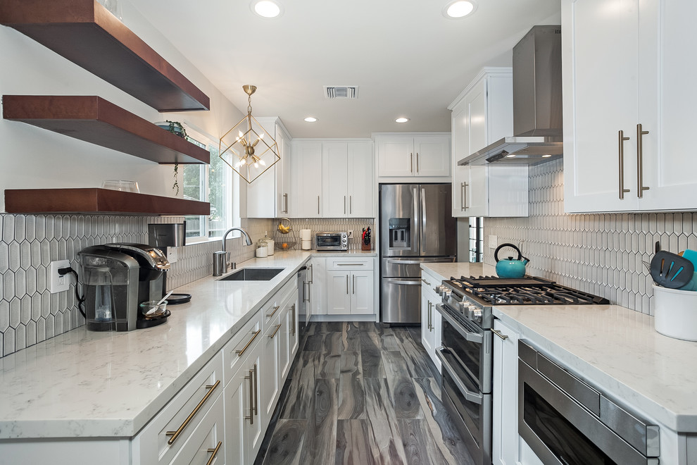 Photo of a large modern galley eat-in kitchen in Los Angeles with an undermount sink, beaded inset cabinets, white cabinets, marble benchtops, white splashback, porcelain splashback, stainless steel appliances, vinyl floors, no island, multi-coloured floor and white benchtop.